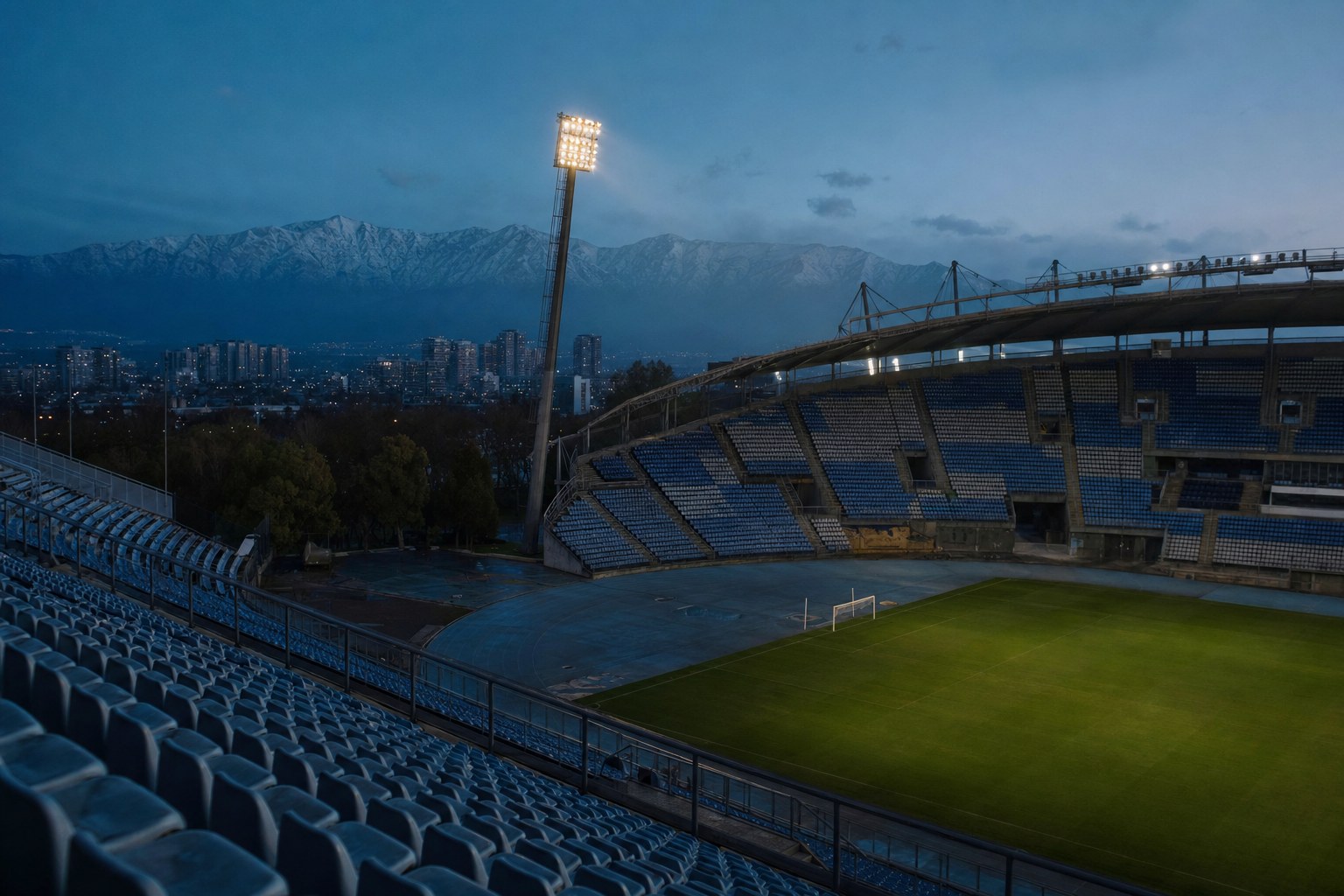 Estadio de fútbol al anochecer con la cordillera de los Andes recortada al fondo